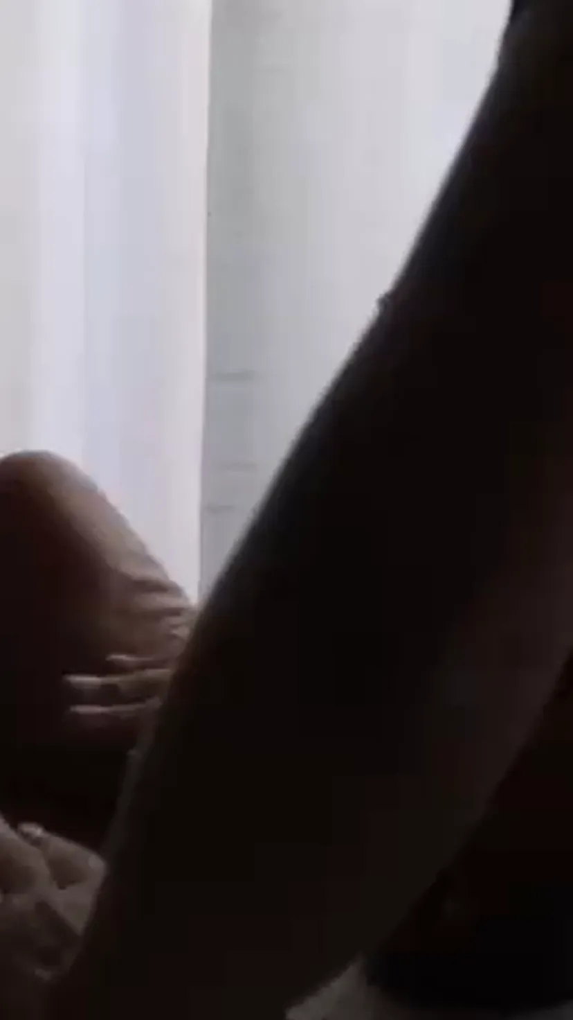 Manos de una terapeuta durante un masaje a domicilio, junto a un frasco de aceite